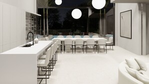 A modern kitchen with a central island, a dining area with chairs, and a large window overlooking a pool. - AMA VILLAS - Luxury Collection -  **BRAND NEW ****35% DISCOUNT AVAILABLE (Rose Hall)
