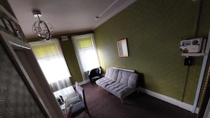 A room with a grey sofa, a black chair, a radiator, and a framed picture on the wall. - Captivating 1-bed Apartment in Blackpool (Blackpool)