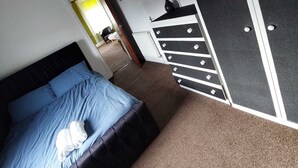 A bedroom with a bed, a dresser, and a door. - Captivating 1-bed Apartment in Blackpool (Blackpool)