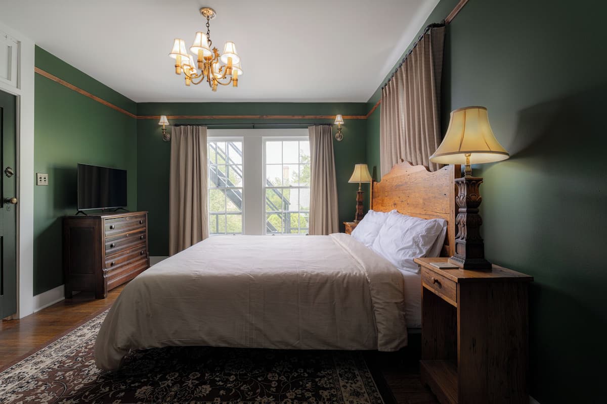 Ein Schlafzimmer mit einem großen Bett, einer Holzkommode und einem Fernseher auf der Kommode.