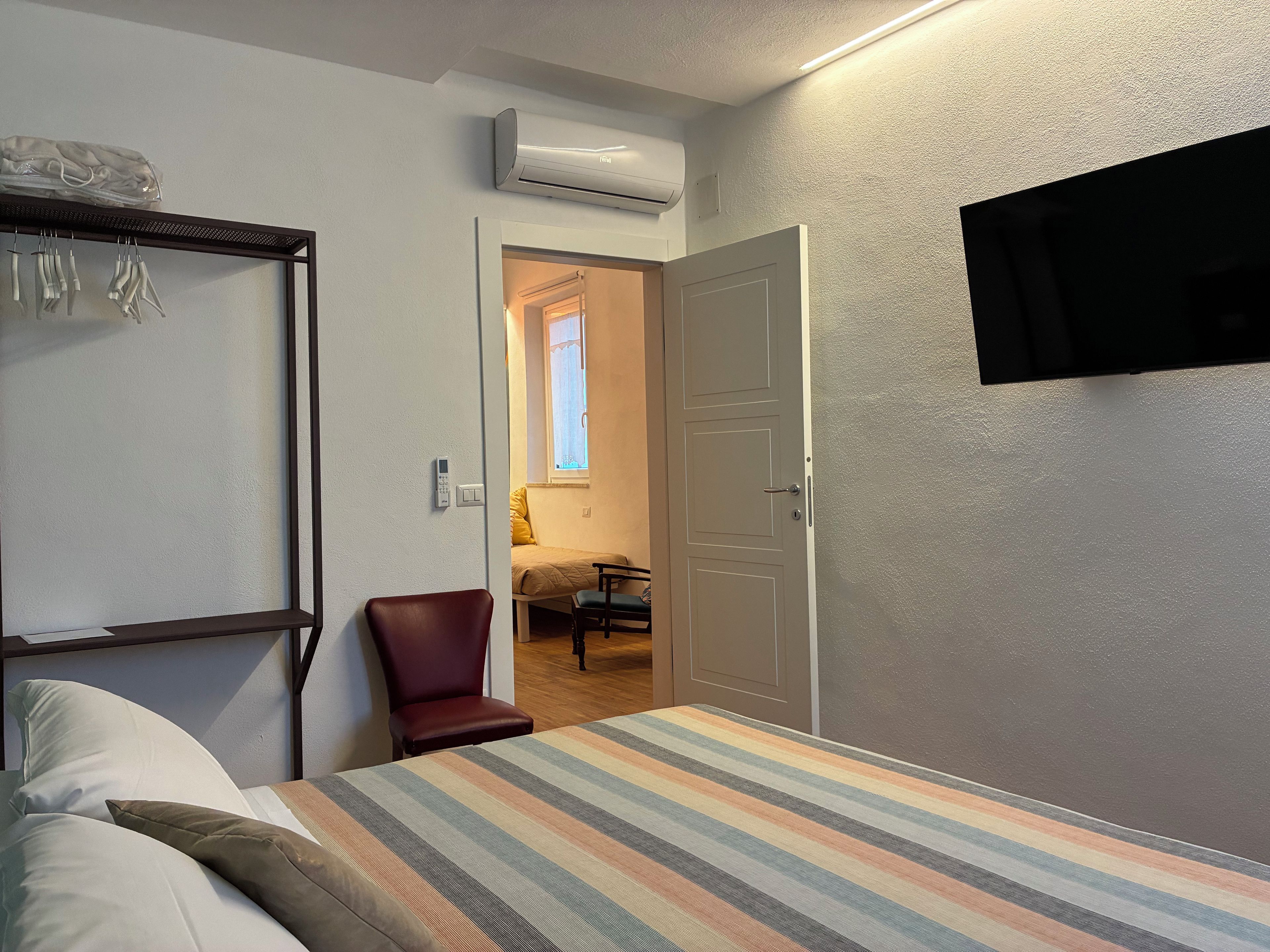 Une chambre à coucher comprenant un lit, une chaise, une armoire, un téléviseur et un appareil de climatisation.