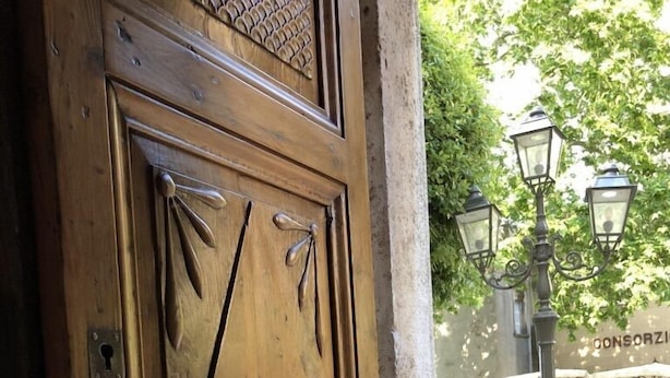 A wooden door with a lion head knocker, a keyhole, and a handle. - DIMOR'A'   ROOMS (Pitigliano)
