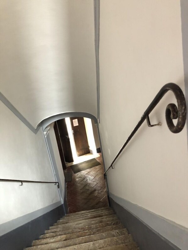 Una escalera con barandilla de metal y suelo con patrón de espiga.
