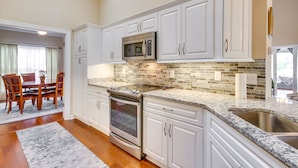 A kitchen with white cabinets, a stainless steel oven, a microwave, and a granite countertop.