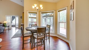 A dining area with a round table, four chairs, and a chandelier.