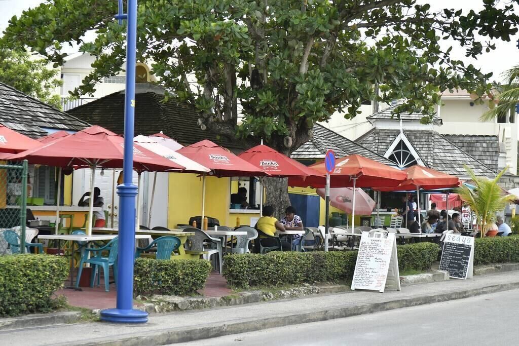 An outdoor café with red umbrellas, tables, and chairs.