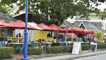 An outdoor café with red umbrellas, tables, and chairs.