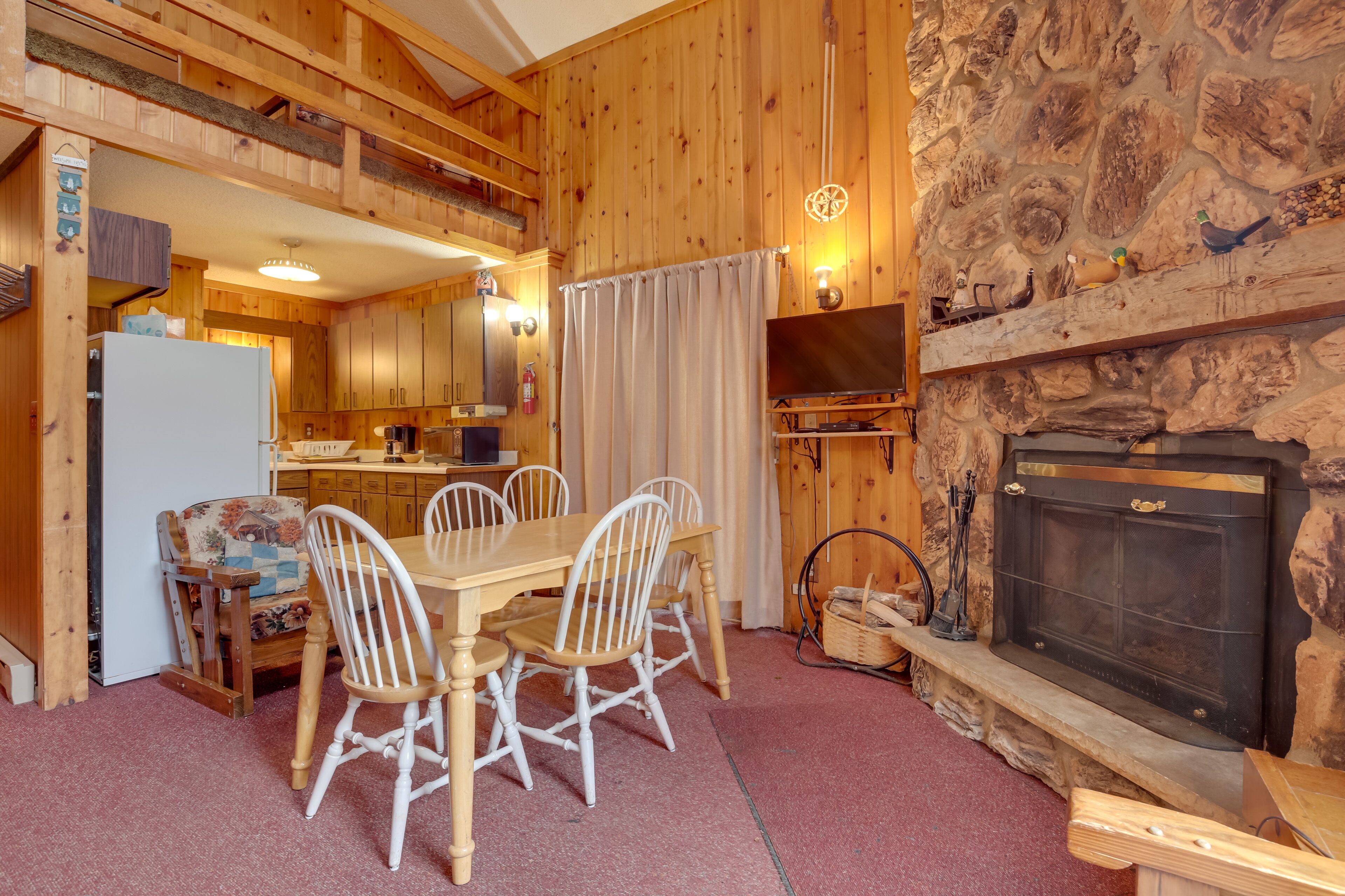 A cozy cabin interior with a dining area, kitchen, and fireplace.