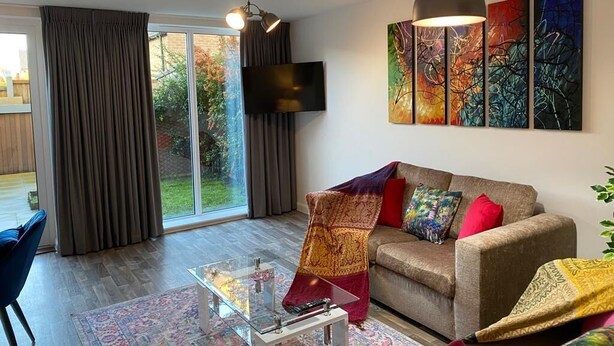 Una sala de estar moderna con un sofá, una mesa de centro de vidrio y un ventanal con cortinas.