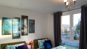 Una habitación de hotel con dos camas, una ventana con cortinas y tres cuadros en la pared.