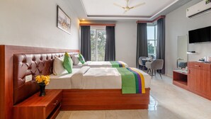 A hotel room with a large bed, a desk, a chair, a TV, and a window with curtains. - Treebo Expo Mart Inn, Greater Noida (Greater Noida)