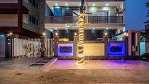 A modern building with a sign for 'treebo' and a tree wrapped in lights. - Treebo Expo Mart Inn, Greater Noida (Greater Noida)