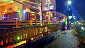 Un restaurant appelé « Harlequin » qui dispose d’une terrasse et est décoré de guirlandes lumineuses.