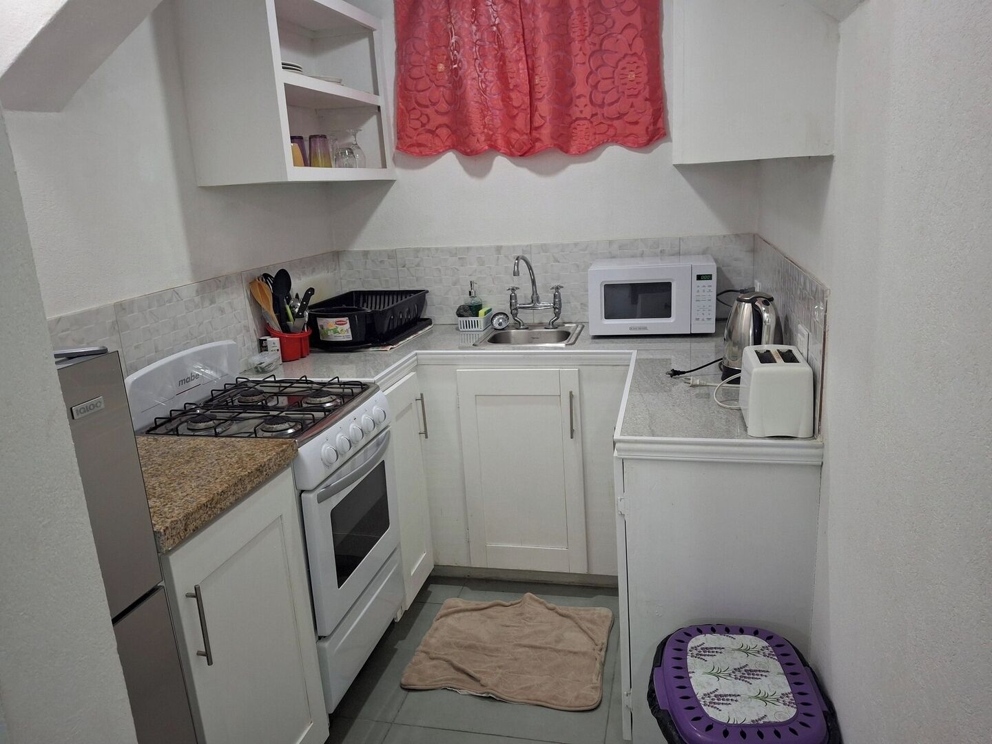A compact kitchen with white cabinets, a gas stove, a microwave, and a toaster.