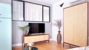 Una sala de estar moderna con televisor de pantalla plana, mueble de madera y un armario grande.