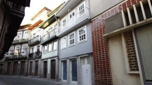 Una estrecha calle adoquinada flanqueada por edificios con balcones y ventanas amplias.