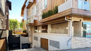 A modern apartment building with multiple balconies, a stone facade, and a visible garage entrance.