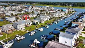 A marina with boats docked, surrounded by residential houses.