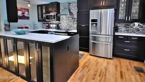 A modern kitchen with dark cabinetry, stainless steel appliances, and a central island.
