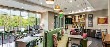 A modern interior with a green sofa, dining tables, and pendant lighting.