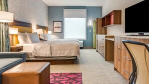 Une chambre d’hôtel comprenant un lit, des tables de chevet, un bureau, une chaise, une télévision et une fenêtre.