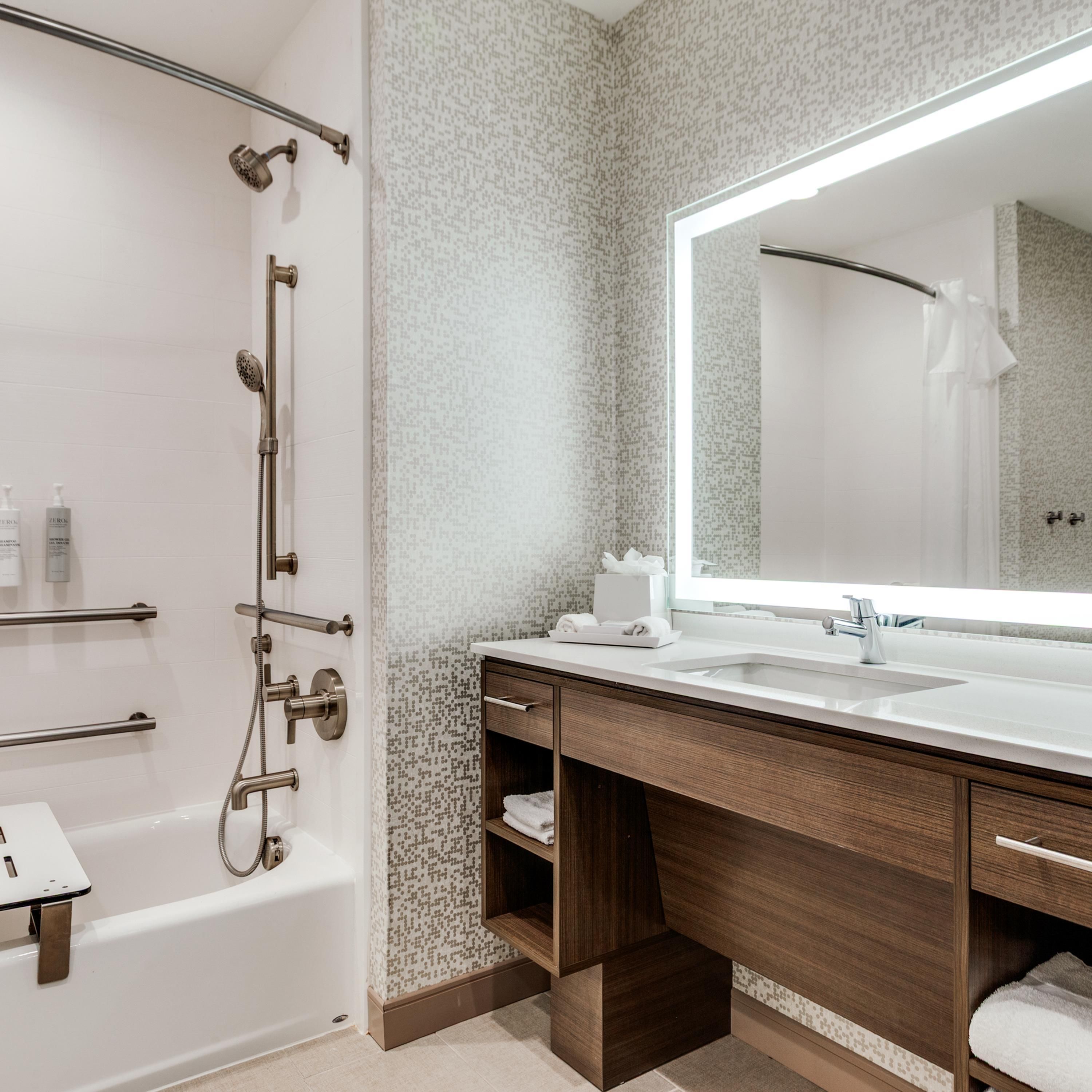 A modern bathroom with a walk-in shower, a large mirror, and a vanity with a sink.