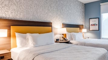 Ein Hotelzimmer mit zwei Betten, einem Nachttisch mit Lampe, einer Uhr und einem gerahmten Bild an der Wand.