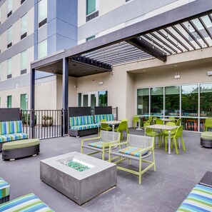Eine Außenpatio-Terrasse mit Sitzgelegenheiten, einer Feuerstelle und einem überdachten Bereich.