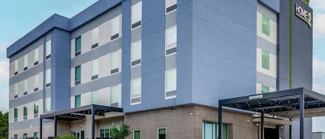 En moderne hotelbygning med et skilt, der siger 'HOME 2 SUITES BY HILTON'.