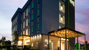Un hôtel moderne, reconnaissable à son enseigne bien visible, à son entrée abritée et à sa façade en briques.