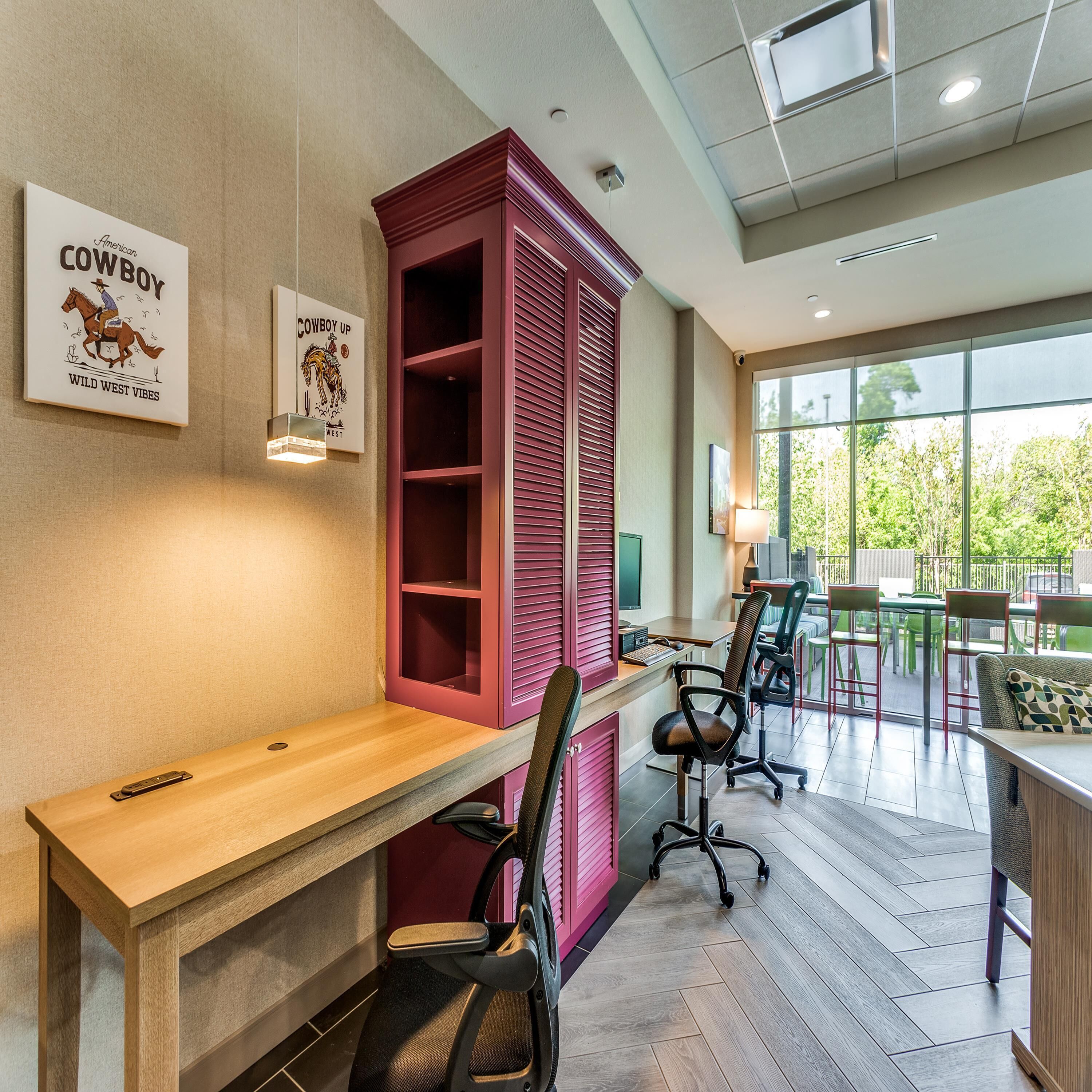 A modern office space with a wooden desk, office chairs, and a red shelving unit.