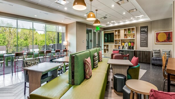 Un intérieur moderne avec un canapé vert, des tables à manger et un coin bar.