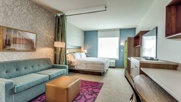 Una habitación de hotel con cama, sofá, escritorio y televisión.