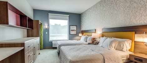 A hotel room with two beds, a desk, and a window with a view.