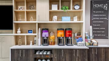 Uma área de recepção de hotel com um espaço para café, um relógio e um aviso que diz 'HOME GUARANTEE'.