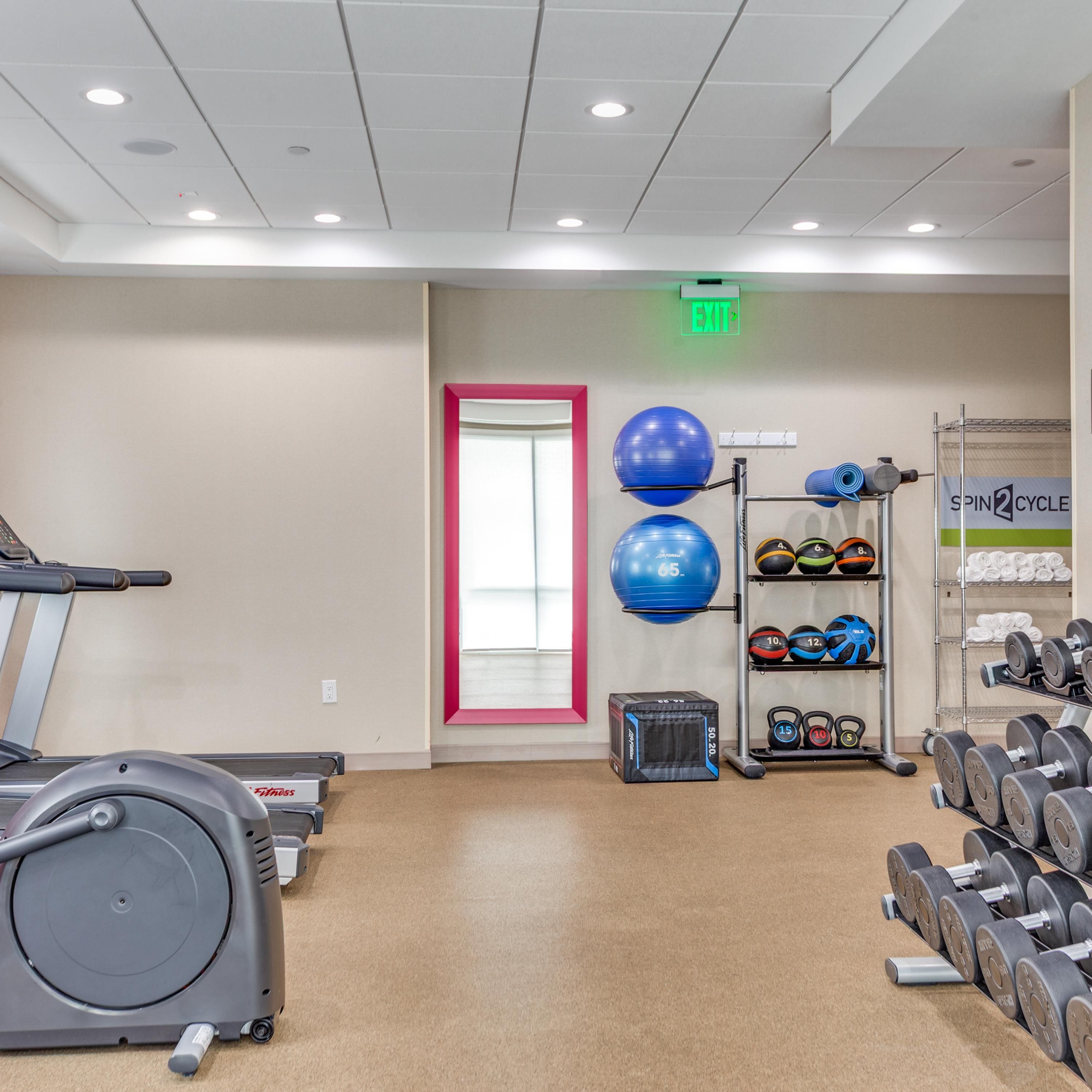 A gym with exercise equipment, including a treadmill, exercise balls, and weight racks.