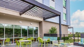 Un espace extérieur aménagé en terrasse, avec des sièges, un foyer et une vue sur la façade du bâtiment.