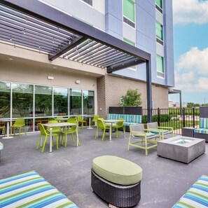 Ein Patio im Freien mit Sitzgelegenheiten, einer Feuerstelle und Blick auf die Außenansicht des Gebäudes.