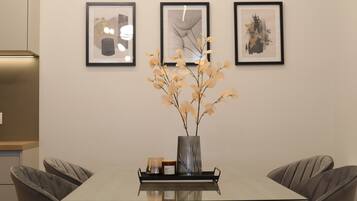 Una mesa de comedor con un florero, una obra de arte enmarcada en la pared y una lámpara moderna.