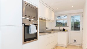 Una cocina moderna con electrodomésticos de acero inoxidable, armarios blancos y un ventanal que proporciona luz natural.