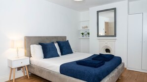 Un dormitorio moderno con cama, mesita de noche y espejo.