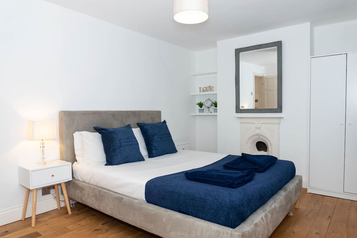 A modern bedroom with a bed, bedside table, and a mirror.