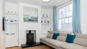 Una sala de estar moderna con un sofá, chimenea y estantes decorativos.