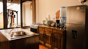 Una cocina con un refrigerador de acero inoxidable, dispensador de agua, estufa y pileta.