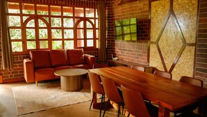 Una habitación acogedora con una mesa de comedor de madera, un sofá de cuero y un ventanal con vistas a la vegetación.