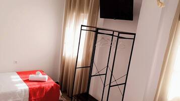Een hotelkamer met twee bedden, een aan de muur bevestigde televisie en een hanglamp.