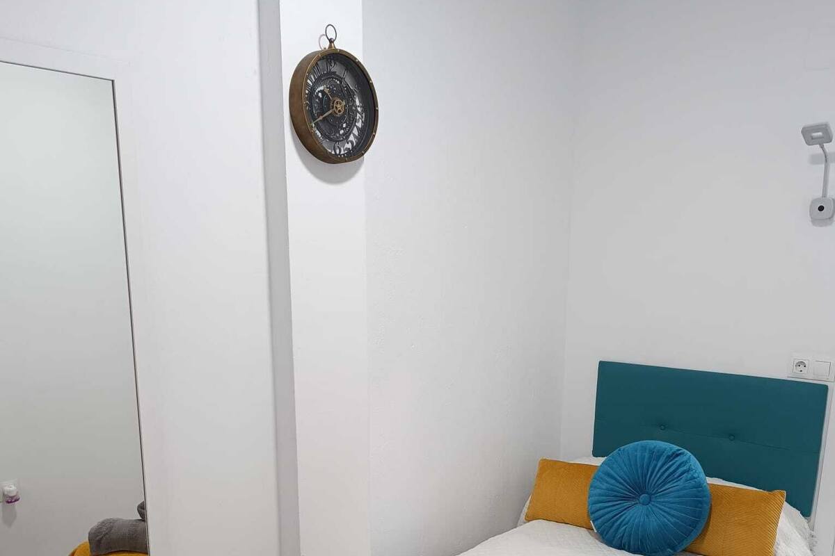 A bedroom with a bed, a mirror, and a wall clock.
