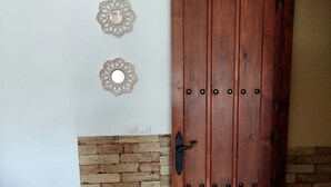 Eine Holztür mit Metallgriff, eine Ziegelwand und drei dekorative Wandspiegel.