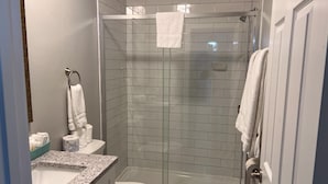 Ein modernes Badezimmer mit einer gläsernen Duschkabine, Toilette und Waschbecken mit Granitplatte.