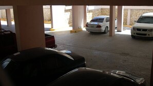 Un parking souterrain où plusieurs voitures sont garées sous une structure soutenue par des piliers.